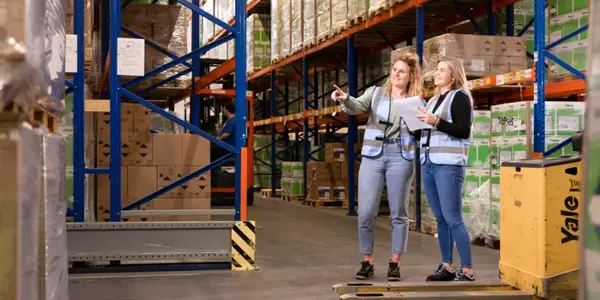 Twee Mensen Lachen In De Supply Chain Omgeving Met Nrg Office Veiligheidshesjes Aan